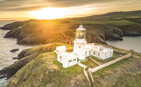 scenic lighthouse on coastal cliffs with sunset and ocean view three beams of light