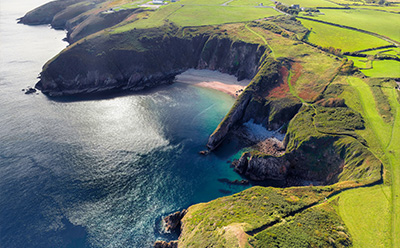 aerial view of a rugged coastline with green cliffs and a sandy beach surrounded by crystal clear water showcasing the beauty of nature and coastal landscapes 2 seaside locations 2 picturesque scenery 2 natural attractions