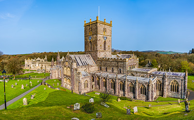 historic church building with tall tower surrounded by gravestones and green grass in a scenic landscape