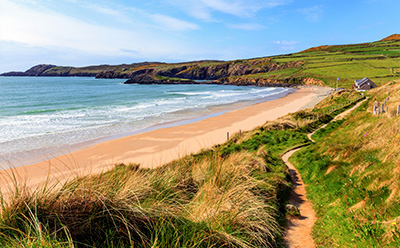 scenic beach view with lush green hills and coastal path showcasing natural beauty of eleven miles of coastline